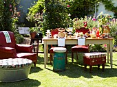 Gedeckter Tisch im sommerlichen Garten mit verschiedenen Sitzgelegenheiten