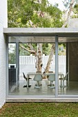 View from garden into purist dining area of concrete house through glass facade