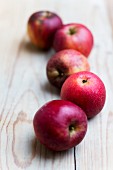 Five red organic apples on a wooden surfac