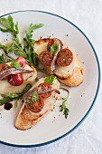 Toasted slices of baguette topped with mozzarella, tomatoes and anchovies