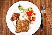Scrambled egg with tomatoes, sausage and French toast, on a white plate