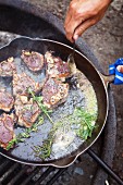 Lamb chops in a pan over a camp fire