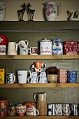 Einfaches Holzregal mit gesammelten Kaffetassen, Teeschalen und Porzellandosen