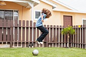 Boy jumping over football