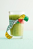 Apple and kiwi smoothie in a glass with a measuring tape