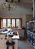 Modern farmhouse kitchen with antique chandelier and cat sitting on bar stool