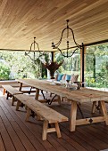 Dining room with rustic table, benches and glass walls with view of garden