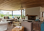 Gemütliches Wohnzimmer mit offenem Kamin, modernen und Vintage Möbeln und einem prachtvollen Blick in die Landschaft