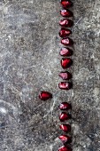 A line of pomegranate seeds on a wooden surface