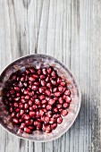 Pomegranate seeds in a metal bowl, from above