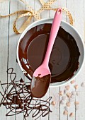 Chocolate sauce in a bowl with a cooking spoon (view from above)