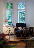 Comfortable reading corner with wing back chair and candle lantern on platform in window bay