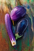 Three assorted aubergines on a wooden surface