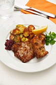 Wiener Schnitzel (breaded veal escalope from Vienna) with roast potatoes, cranberries and lemon