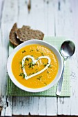 Carrot soup garnished with a heart of sour cream and cress