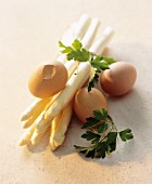 A still life of ingredients featuring white asparagus and eggs