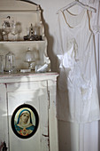 Altes Unterkleid hängt neben Kommode mit Madonnenbild
