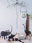 Black, wire sculptures of African animals and other wire objects against white wall
