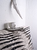 White cup on top of grey and black scatter cushion