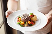 Man serving Plate with Beef Filet and Sauteed Vegetable