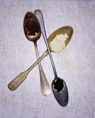 Old silver spoons on a white surface
