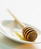 A honey dipper with honey on a plate