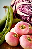 White turnips, red cabbage and beans on a wooden board