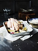 Chicken ready for roasting, in a roasting tin with lemons
