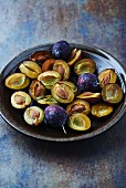 whole and halved plums on a ceramic plate