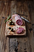 Salami alla cacciatora with marinated caper berries on a chopping board
