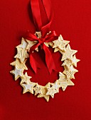 Wreath made of star cookies with a red ribbon in front of a red background
