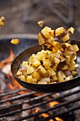 Bratkartoffeln in Pfanne über Campinggrill zubereiten