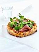 Mini pizza with lamb's lettuce and dry-cured ham