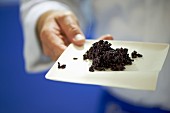 Man holding a plate with riso venere (black rice, Italian)