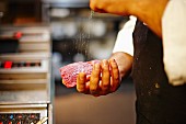 A chef seasoning beef steak with salt