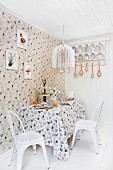 Österlich geschmückte Essecke in der Küche mit Hühnermotiv auf Tapete und Tischdecke und weissen Vintage Stühlen