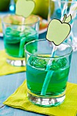 Glasses of sweet woodruff pop with drinking straws decorated with cut-out paper apples