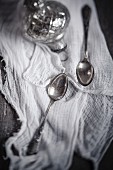 Two teaspoons and a silver Christmas bauble on a muslin cloth