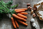 A still life featuring carrots, shallots and garlic