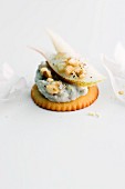 A cracker topped with Gorgonzola cream, pear and nuts