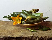 Zucchini mit Blüten in Holzschale