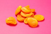 Dried apricots on a bright pink surface