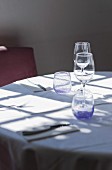 Licht fällt durch ein Fenster auf einen Restauranttisch mit Besteck und Gläsern