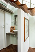 Schwebende Treppenstufen aus dreieckigen Holzprofilen und freistehende Trennwand vor einem Waschtisch