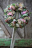 Wreath of flowers with hydrangeas and sprigs of berries hanging on wooden lath