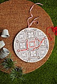 Round door decoration with lace pattern, partly embroidered with red wool thread