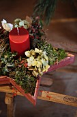 Wintry arrangement of red candle and natural materials in wooden star