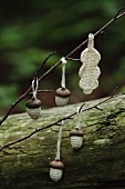 Crocheted acorns and leaf hanging on twig