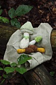 Crocheted toadstools lying on cloth in woodland
