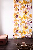 Floral length of wallpaper on white wall, vintage trunk and wicker stool